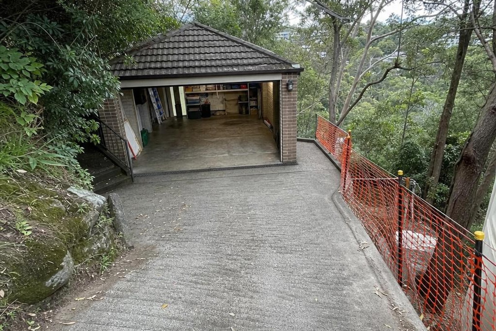 Steep leafy suburban driveway with safety mesh leading to an open garage