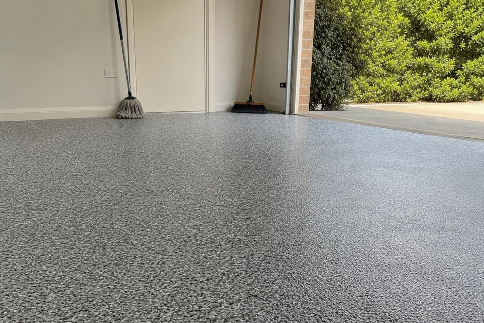 Grey decorative flake garage floor with cleaning broom near the wall