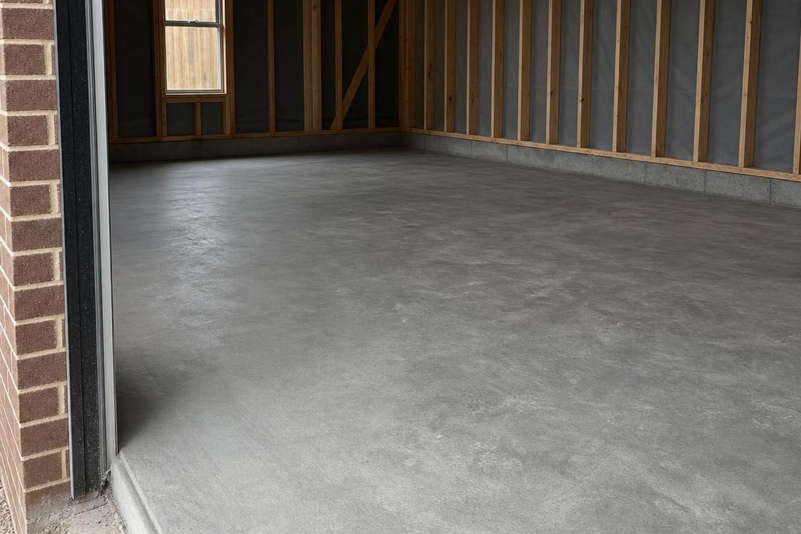 Bare newly poured concrete slab inside an unfinished timber-framed garage
